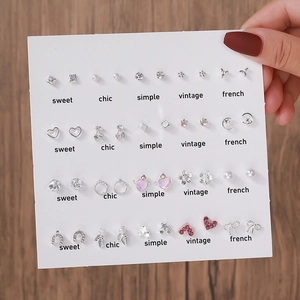 Détail de 20 paires de boucles d'oreilles argentées avec perles et pierres cœur roses