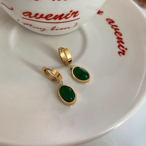 Detailed close-up of emerald green pendant earrings with gold-toned stainless steel hoops