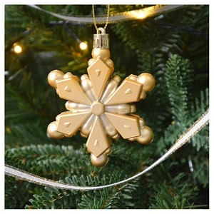 Macro detail of golden snowflake ornament hanging on a Christmas tree branch