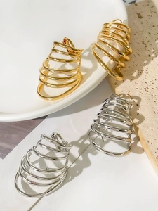 Detail of gold and silver multi-layer spiral earrings on a minimalist stone surface