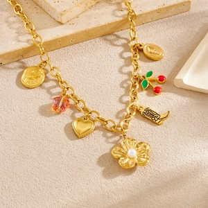 Gold-plated chain necklace featuring cherry, flower, boot, and coin pendants on stone decor