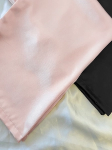 Nahaufnahme von Satin-Schlafhose mit glänzender Textur in Rosa, Schwarz und Champagner