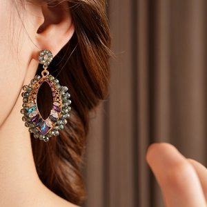 Gros plan de boucles d'oreilles bohèmes serties de cristaux colorés sur un mannequin