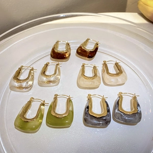 Flat lay of five pairs of U-shaped resin and gold metal earrings in assorted colors