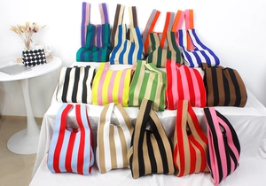 Close-up of vibrant striped knit tote bags in various colors displayed in a modern home setting