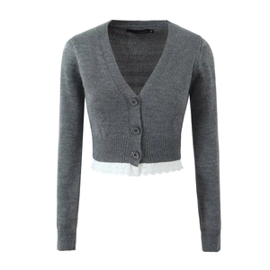 Détail d'un gilet gris en tricot à col en V avec bordure en dentelle blanche et boutons
