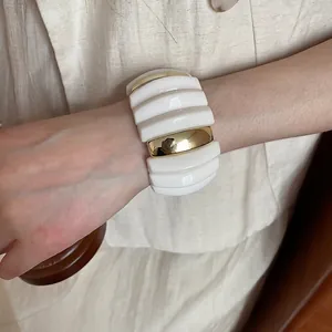 Chunky acrylic and gold metal wide segmented bangle bracelet with wavy textured design