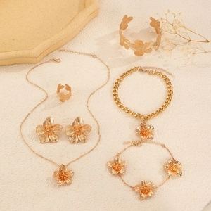 Golden floral textured jewelry set featuring necklace bracelet earrings and ring on tray