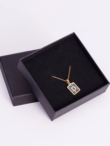 Detailed close-up of a square gold letter D pendant with dark shell inlay in a gift box