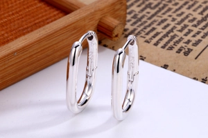 Close-up of polished S925 sterling silver U-shaped hoop earrings with hallmark engraving