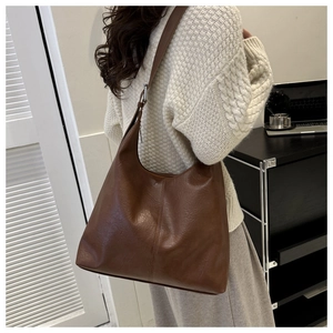 Brown textured leather tote bag showing large capacity and stitching details worn by model