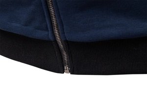 Detail of navy knit jacket hem featuring black ribbed cuff and premium metal zipper
