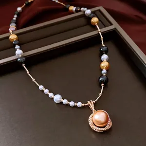 Collier de perles multicolores avec grand pendentif doré champagne sur plateau bijoux