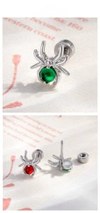 Macro view of spider-shaped cartilage studs with green and red stones and screw-back closure