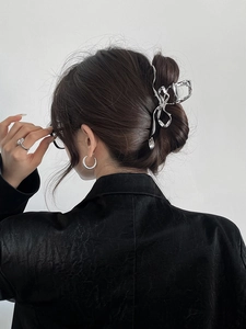 Detail of silver ribbon bow hair claw clip styled on a woman's dark hair with black coat