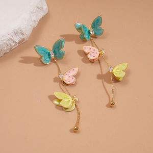 Vue macro des boucles d'oreilles à pompons avec trois papillons en émail et zircons