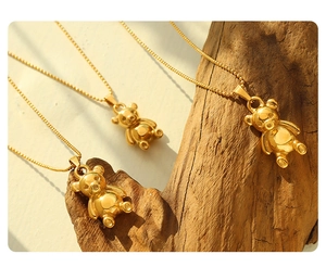 Macro detail of 18K gold-plated bear pendant necklace on natural wood display