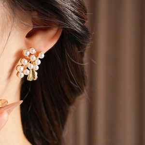Macro shot of vintage style gold leaf earrings with clustered white pearls on model