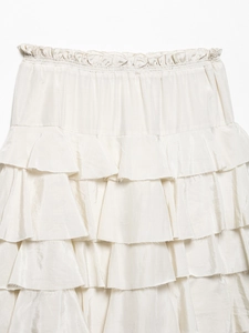 Detailed view of cream tiered satin skirt showing layered ruffles and elastic waistband