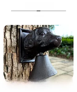 Detail display of a vintage cast iron dog head door bell mounted on a tree in a garden