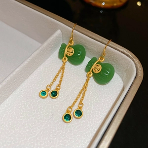 Makroaufnahme chinesischer Gold-Quastenohrringe mit grünen Fu-Beutel-Anhängern