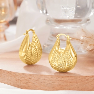Gros plan de boucles d'oreilles dorées en forme de larme avec motif texturé en losange