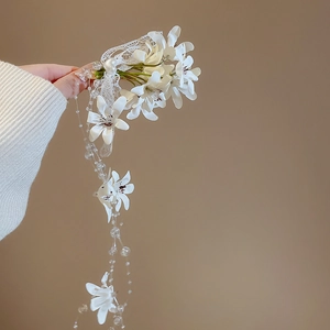 Close-up of white fabric flowers with lace and elegant pearl tassels for hair styling