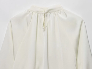 Detail of elegant cream crepe blouse showing high collar neckline and silk-like fabric texture