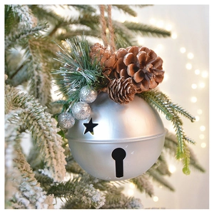 Detail of silver Christmas bell with pine cones and needles on snowy tree branch