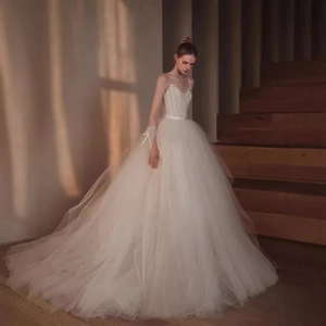 French lace wedding dress with large trail and bow straps on a wooden staircase