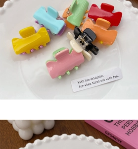 Close-up of colorful candy-toned small hair claws in a white decorative porcelain dish