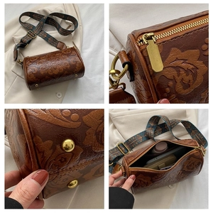 Detailed close-up of brown embossed floral leather cylinder bag with vintage hardware