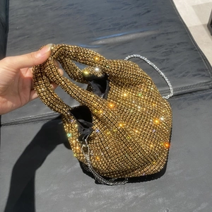 Detail of gold rhinestone bucket bag with sparkling crystals and fine silver metal chain