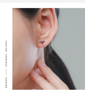 Gros plan de boucles d'oreilles en argent avec pierre rubis en forme d'ailes d'oiseau