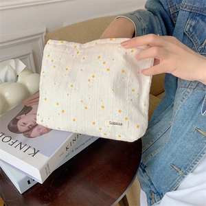 Floral cotton makeup bag with daisy print held by a model in a lifestyle setting