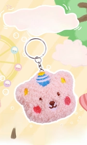 Detailed close-up of a pink plush bear keychain with a striped party hat and metal ring
