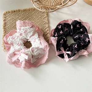 Detail of white and black lace scrunchies with pink bow accents and ribbon trim