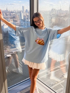 Λεπτομερής όψη γαλάζιου βαμβακερού t-shirt με σχέδιο κρουασάν και λευκή πλισέ φούστα