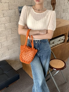 Detail of orange handwoven bucket bag featuring a white drawstring inner lining