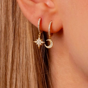 Close-up of gold star and crescent moon earrings with cubic zirconia on female model