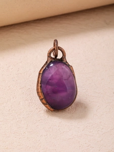 Close-up of a vintage oval purple amethyst pendant set in a textured bronze frame