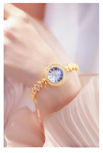 Close-up of gold chain watch with diamond bezel and white Roman numeral dial for women