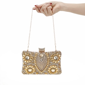 Detail of evening clutch featuring golden floral crystal patterns and thin metal chain