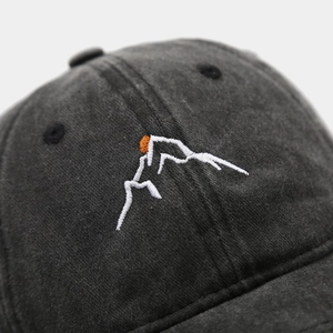 Detailed close-up of mountain and sunset embroidery on washed cotton baseball cap