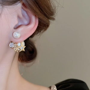 Close-up of star and clover drop earrings with pearls on model's ear