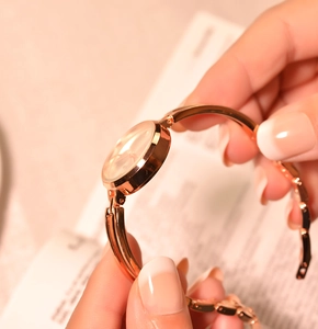 Close-up of a stylish rose gold quartz watch with a small dial on a female wrist