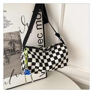 Detail of checkered crossbody bag featuring a neon rope zipper pull and Soraka brand tag