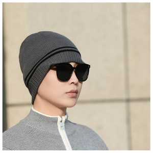 Detail of grey knitted winter hat with black stripes and thick thermal fleece lining