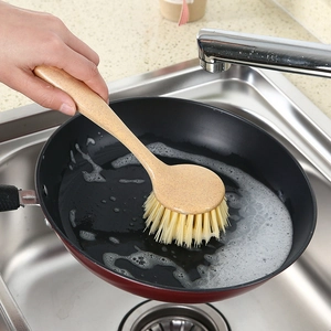 Wheat straw kitchen dish brush with long handle cleaning a soapy pan in a sink