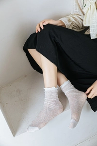 Close-up of white lace mesh crew socks with ruffle cuffs and delicate hollow out design